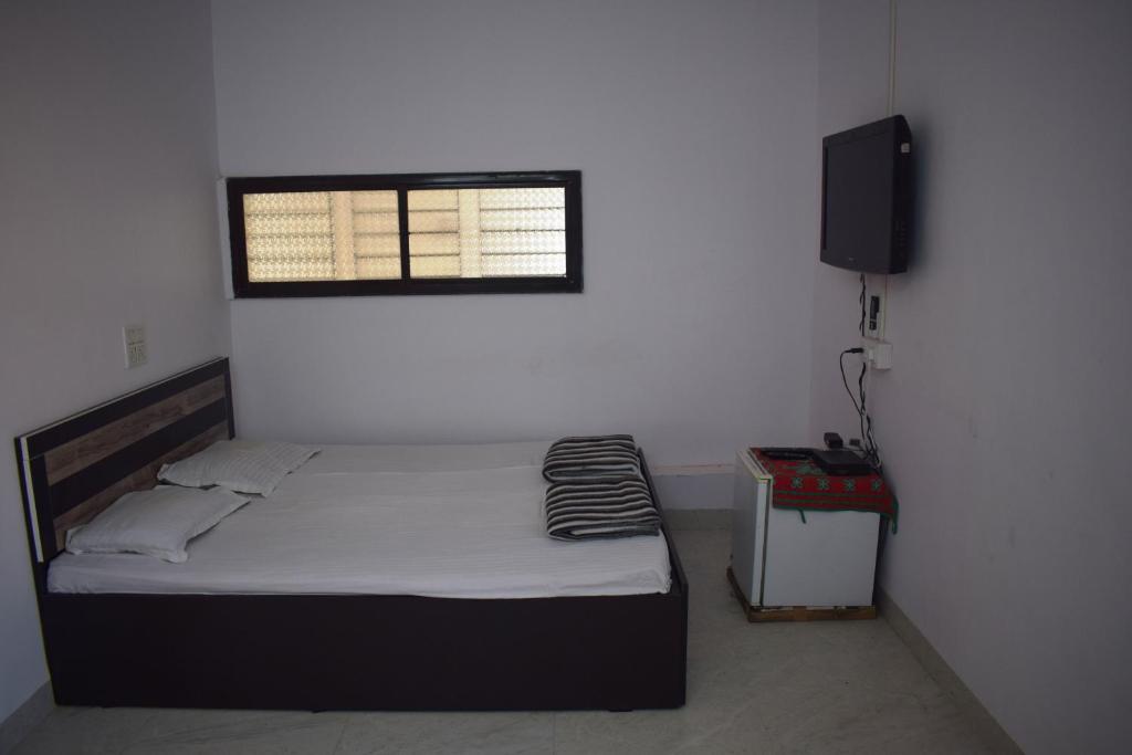 een slaapkamer met een bed, een raam en een televisie bij Adyeshwari Home Stays, Aurangabad in Aurangabad