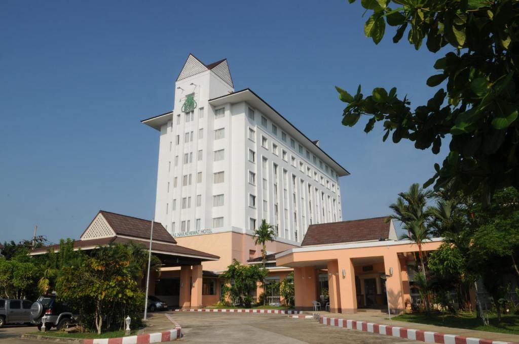 um grande edifício branco com uma torre de relógio no topo em The Imperial Narathiwat Hotel em Narathiwat