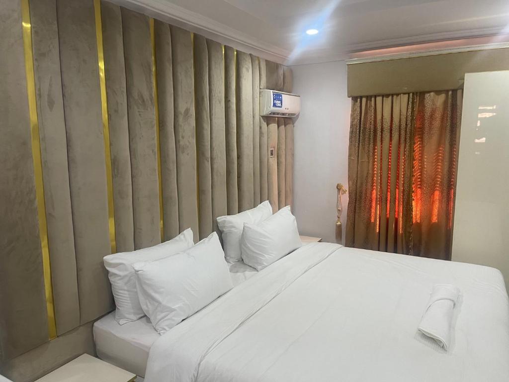 1 dormitorio con 1 cama blanca grande con almohadas blancas en White Gold Hotel, en Ikeja