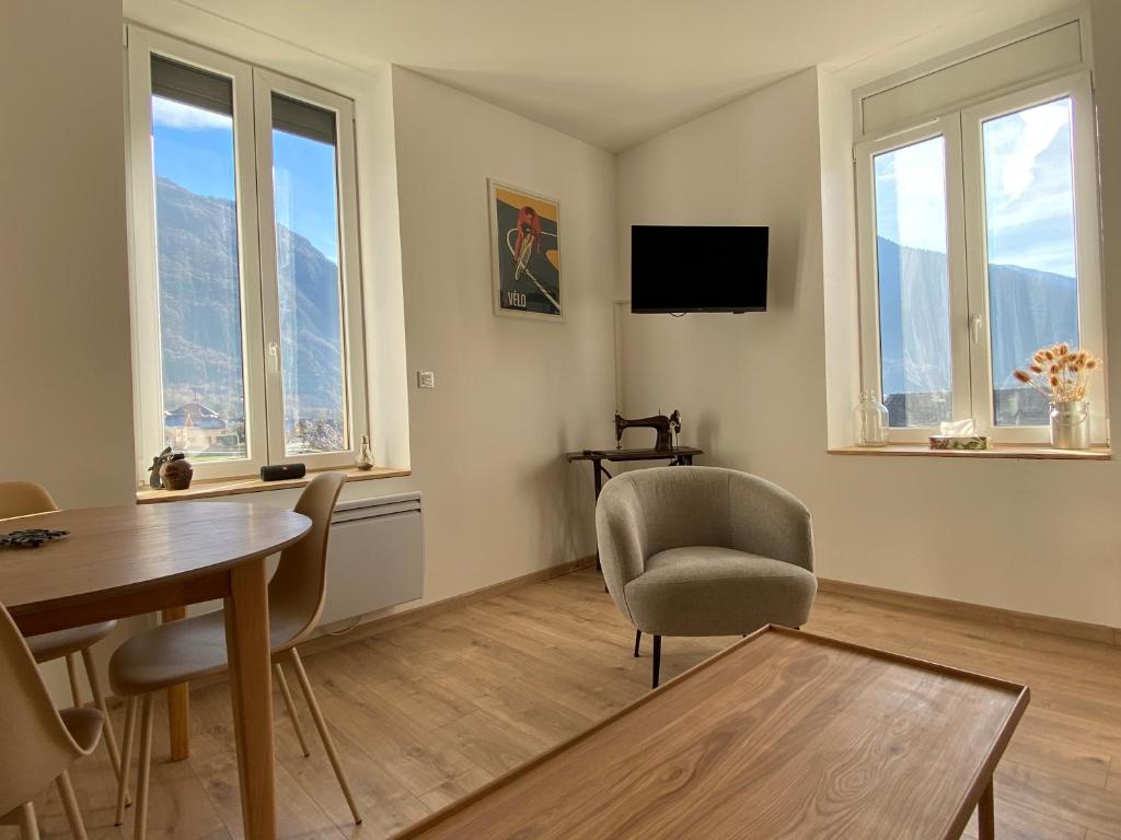 a living room with a table and chairs and windows at L'Augustine - Spa privé & Vue Montagne in Saint Avre la Chambre