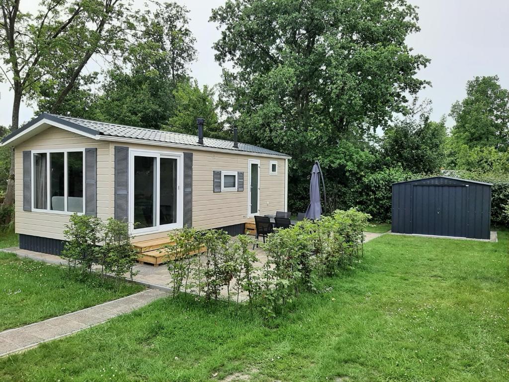 a tiny house in a yard with a garden at Gezellig chalet op een prachtige plek in Drenthe met vrij uitzicht in Tynaarlo