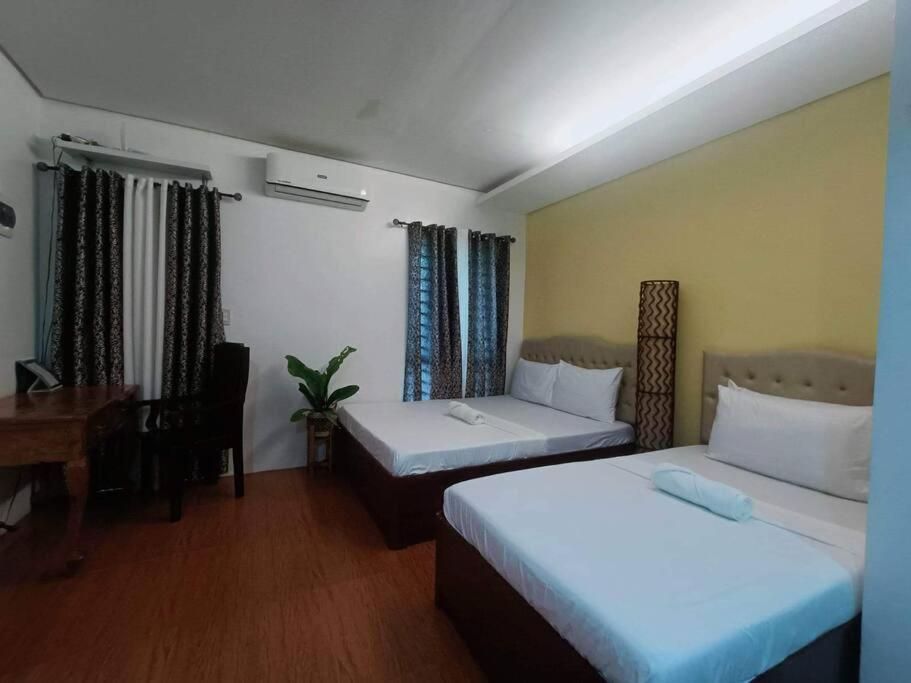 a hotel room with two beds and a desk at 1 - Affordable Family Place to Stay In Cabanatuan in Cabanatuan