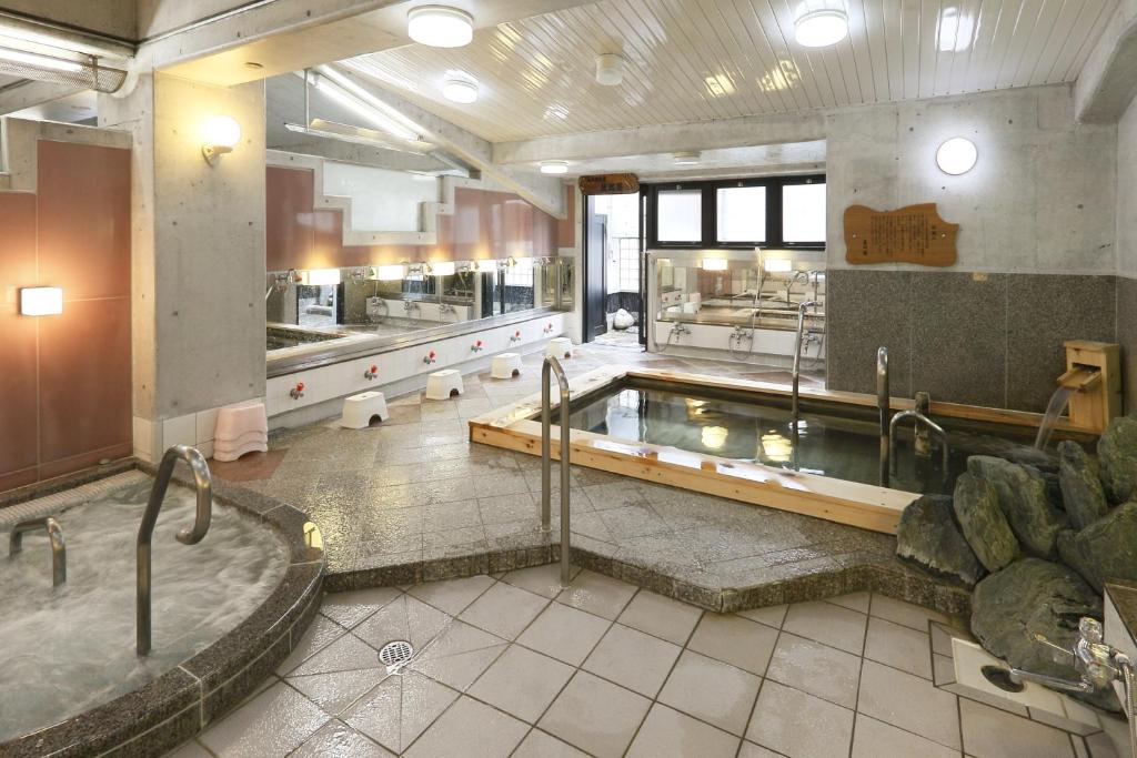 La grande salle de bains est pourvue d'un bain à remous et d'une baignoire. dans l'établissement Suminoyu Hotel, à Nagoya