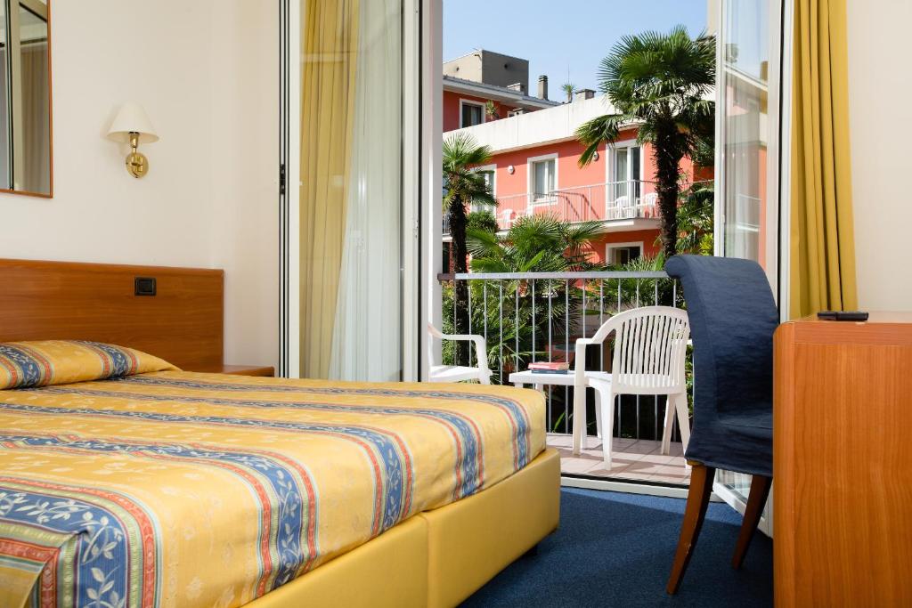 Habitación de hotel con cama y balcón en Brione Green Resort, en Riva del Garda