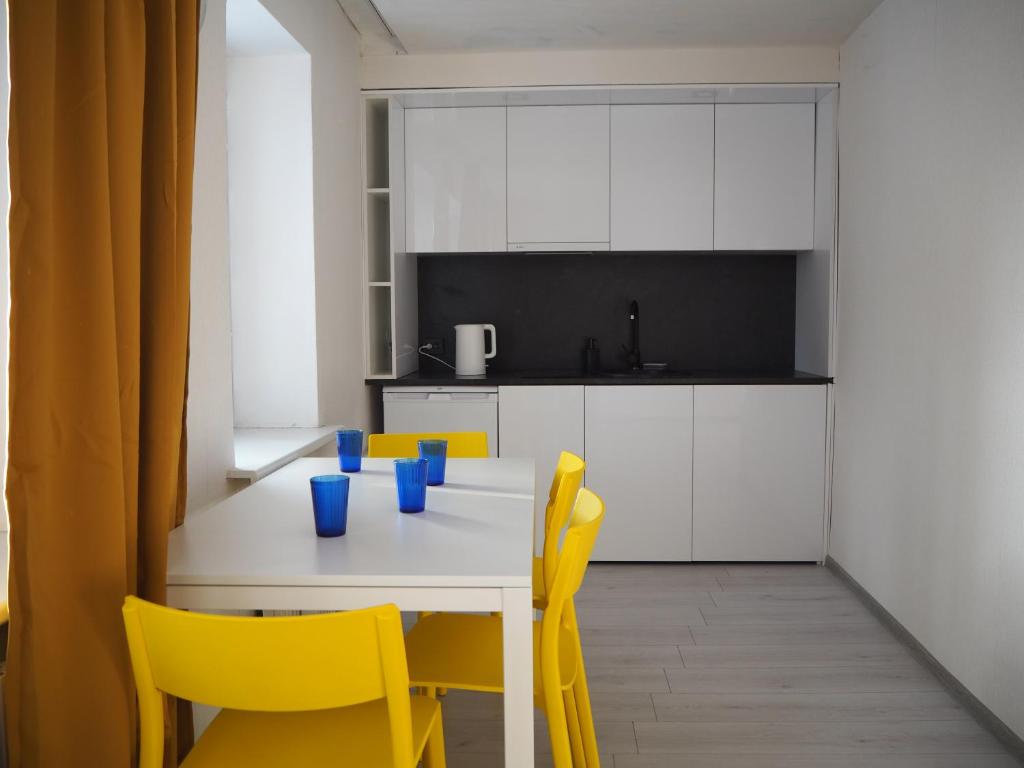 a kitchen with a white table and yellow chairs at Sunny apartment with lake and forest view in Visaginas