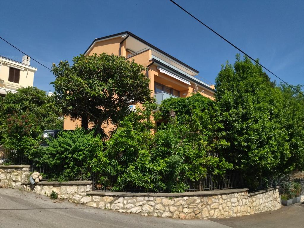 una casa con árboles y una pared de piedra en Vila Zdenka Apartmants, en Crikvenica