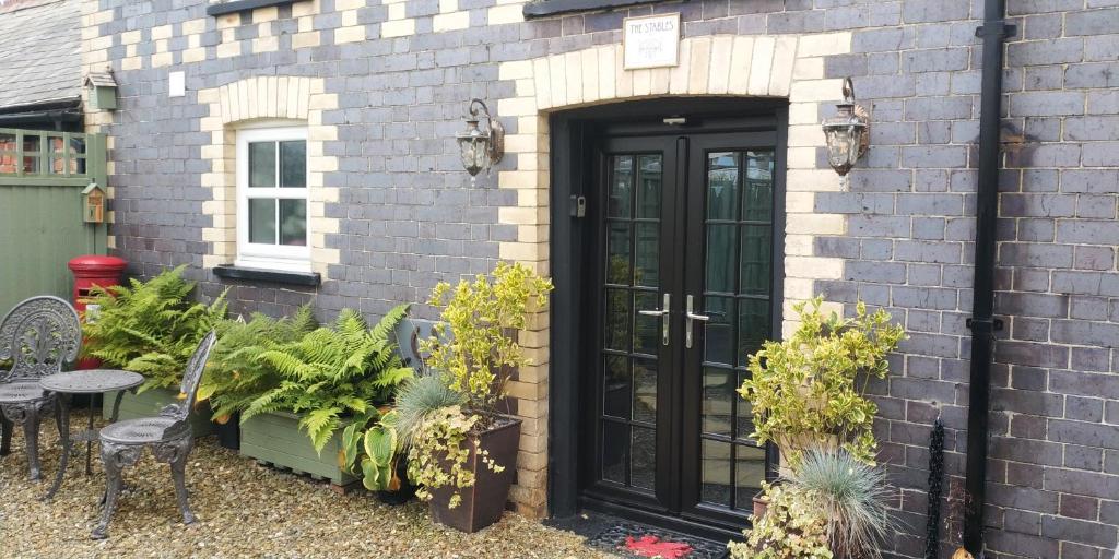 a black door on a brick building with plants at The Stables in Tregaron