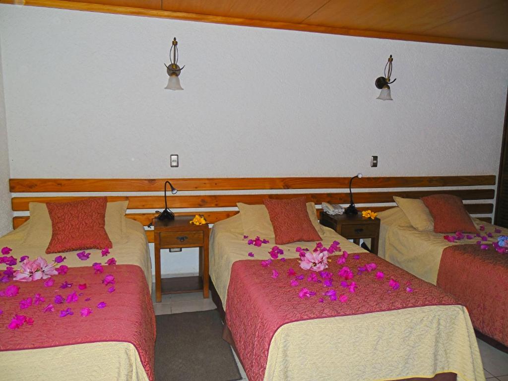 a hotel room with two beds with flowers on them at Hotel Puku Vai in Hanga Roa