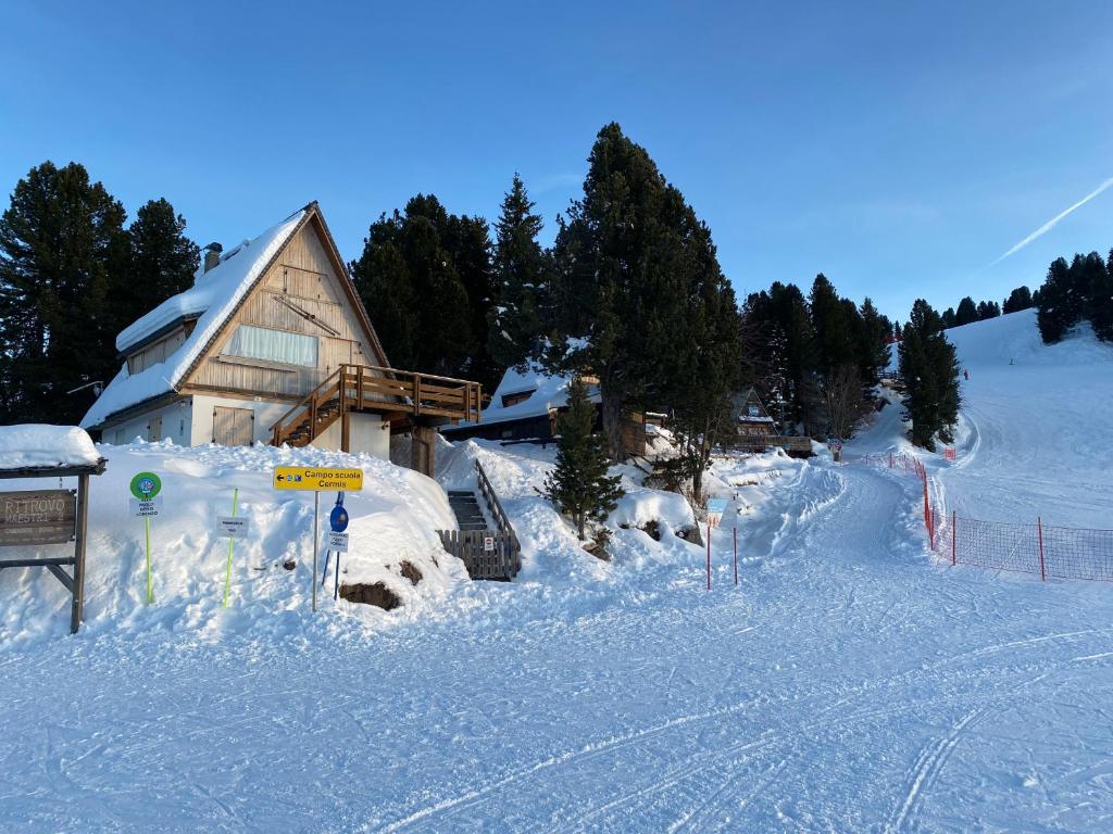 a snow covered ski slope with a building in the background at Cozy Mountain Chalet in Cavalese