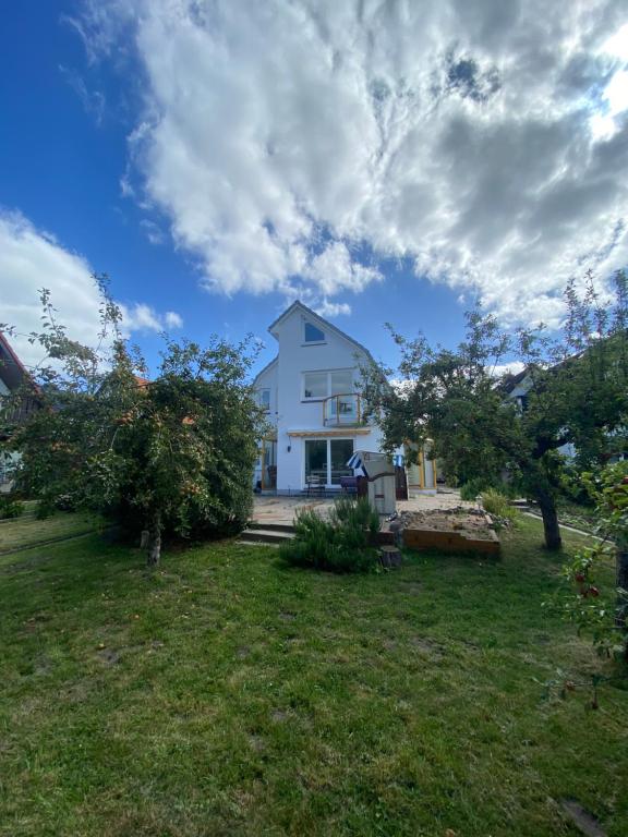 ein weißes Haus in einem Hof mit Bäumen in der Unterkunft Wittinghuus - Urlaub aan de Ostsee in Timmendorfer Strand