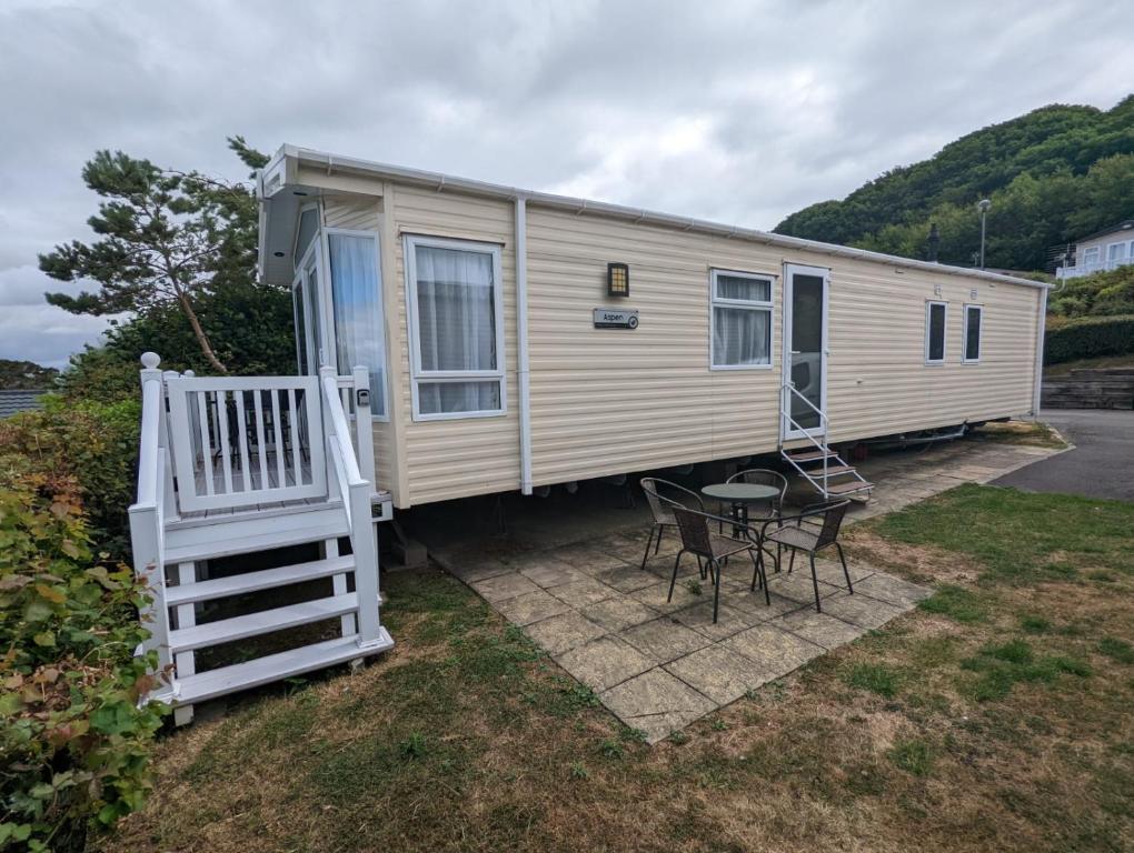 a mobile home with a porch and a table and chairs at BEAUTIFUL LUXURY Caravan HAVEN LITTLESEA STUNNING VIEWS Sleeps 6 in Weymouth