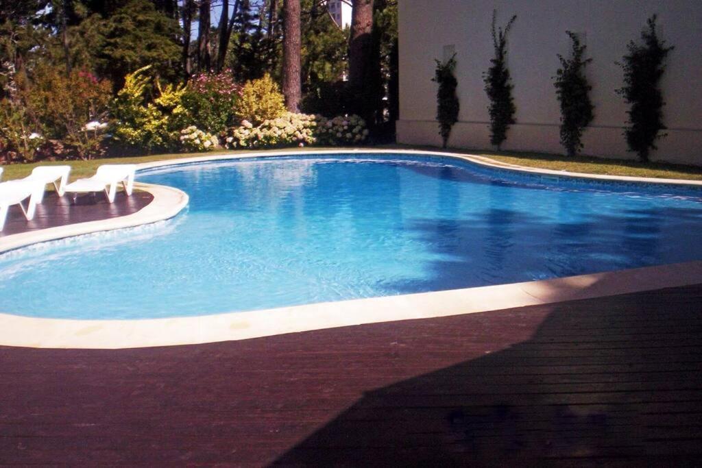 a swimming pool with two white chairs in it at Apto con piscinas, servicios, cochera, wifi in Punta del Este