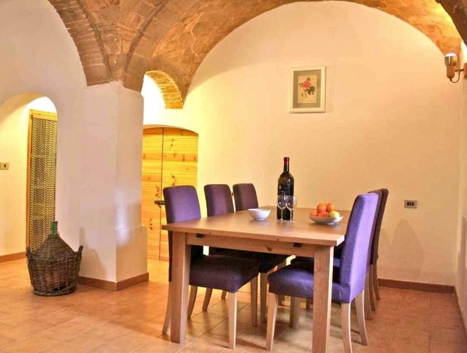 comedor con mesa de madera y sillas moradas en Casa Italica - a quaint getaway in rural Italy, en Corfinio