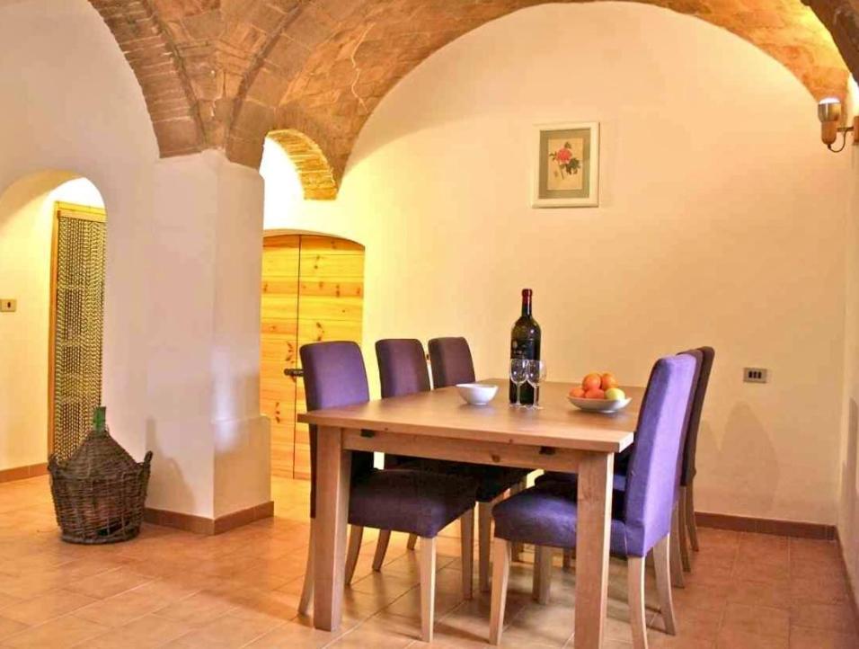 a dining room with a wooden table and purple chairs at Casa Italica - a quaint getaway in rural Italy in Corfinio