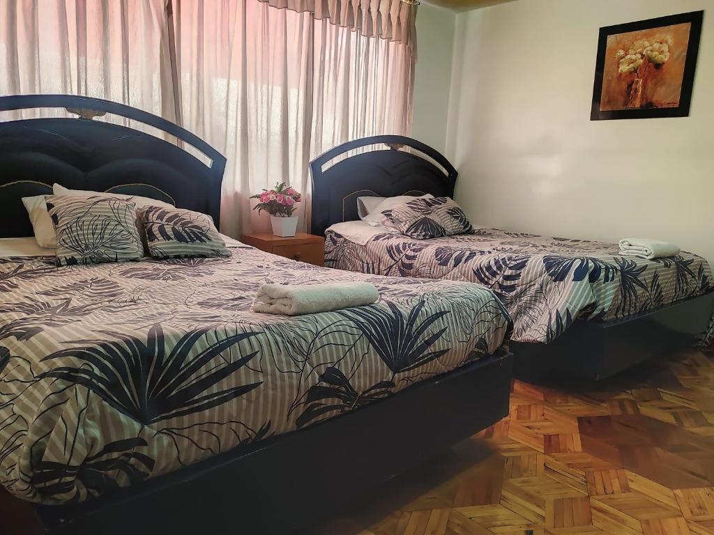 Hotel Altamira Suites - Ibarra في إيبارا: سريرين يجلسون بجانب بعض في غرفة النوم