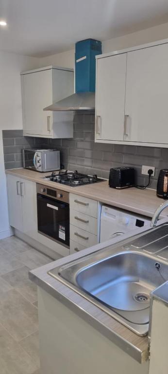 a kitchen with a sink and a stove at Cheerful 3-bedroom home in Sale - free parking on premises in Sale