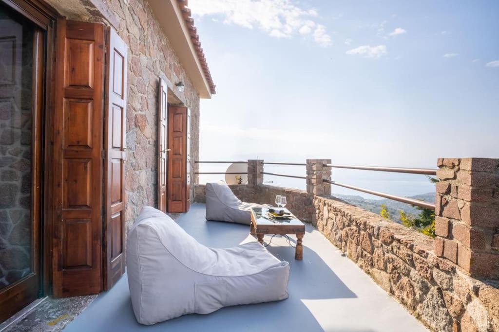 a balcony with couches and a table on a wall at Stone Sunset Villa in Sfendoúrion