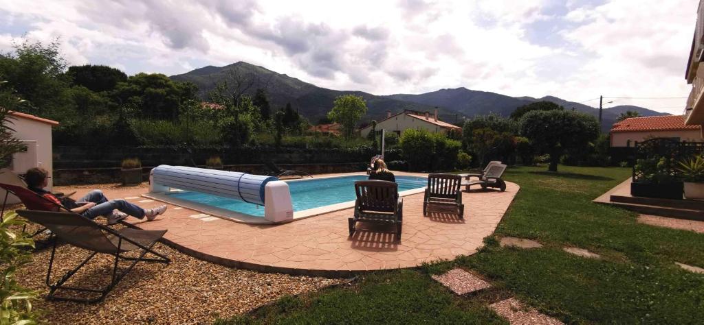 a group of people sitting in chairs near a swimming pool at Chambres d&#39;hôtes et gîtes Al Pati in Sorède