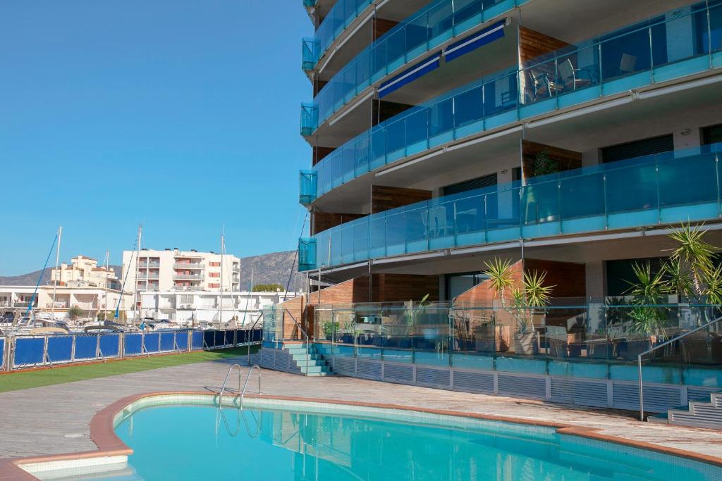 un hotel con piscina frente a un edificio en Moderno y confortable apartamento Port Trebol en Rosas