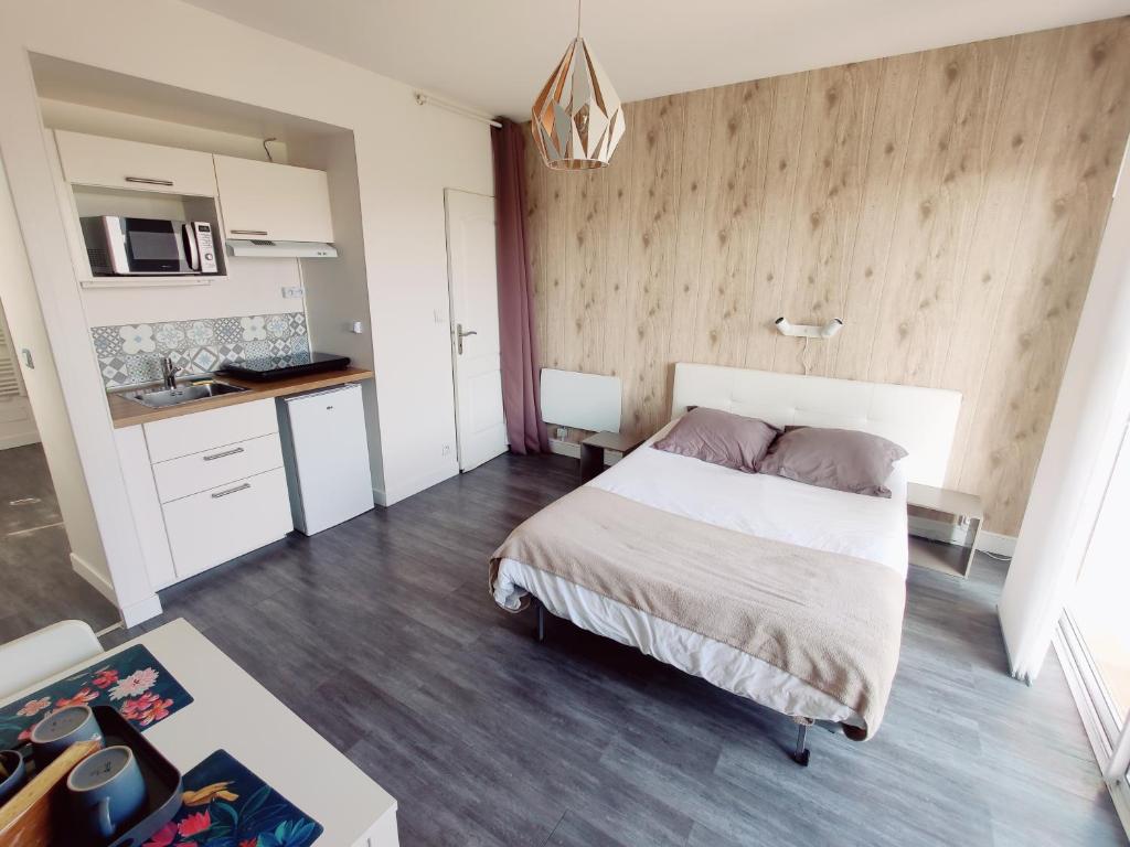 een kleine slaapkamer met een bed en een keuken bij Studio Guest House à 5 minutes de Caen in Fontaine-Étoupefour