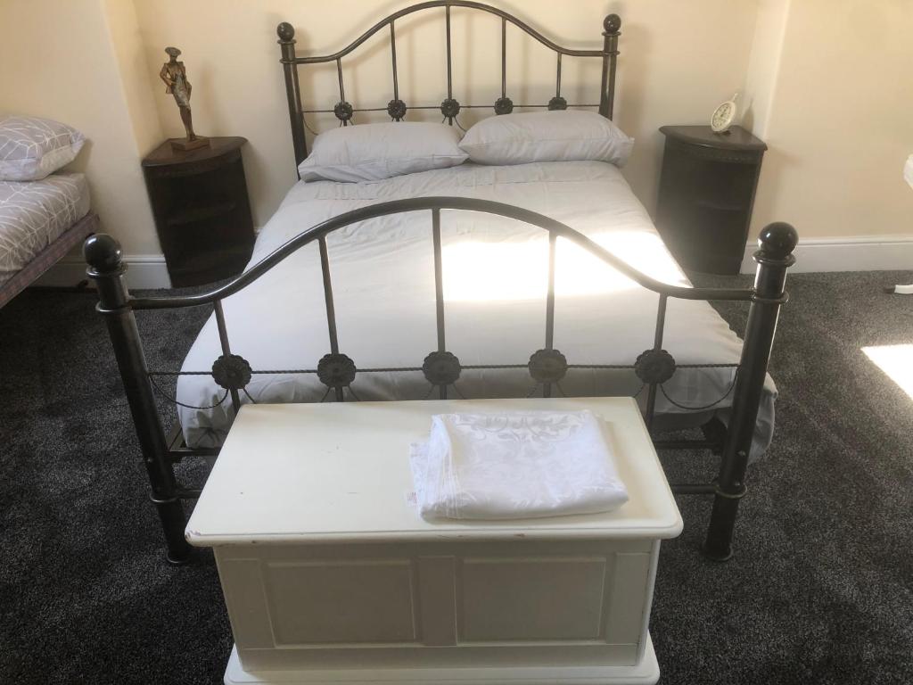 a bed with a black frame and a white bench in a room at Chequers in Doncaster