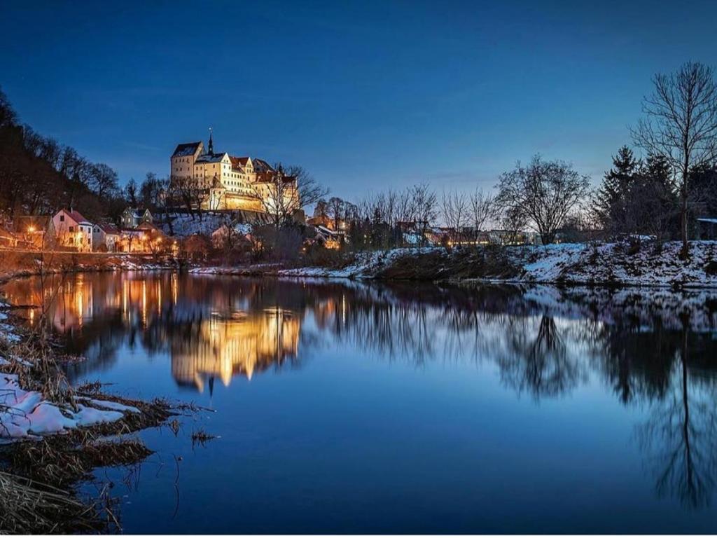 een groot gebouw wordt 's nachts verlicht op een rivier bij Ferienwohnung am Schloss Colditz in Colditz