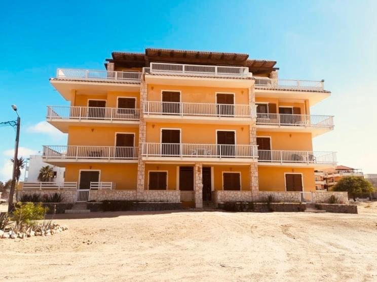 a large yellow building on the beach near the sand at Boavista Beach Apartment in Sal Rei