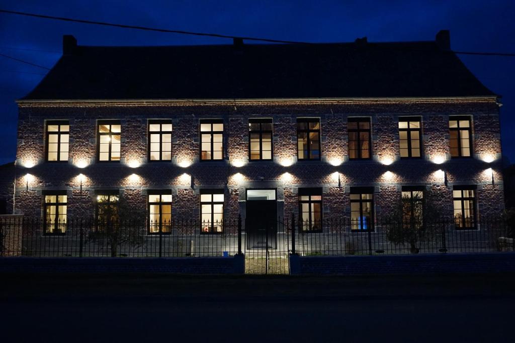 um edifício iluminado à noite com luzes em La Ferme Décroué 