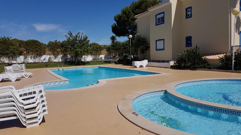 a swimming pool with chairs and a house at ALFELI-AP in Olhos de Água