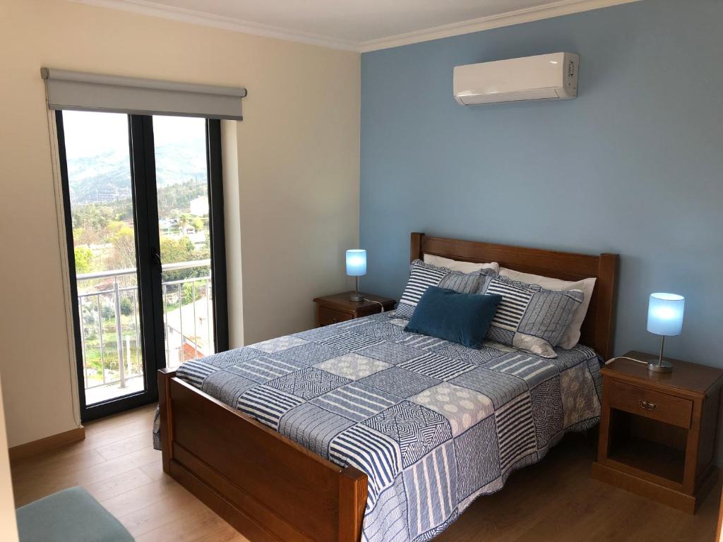 a bedroom with a bed and a large window at Casa da Forja in Aldeia das Dez