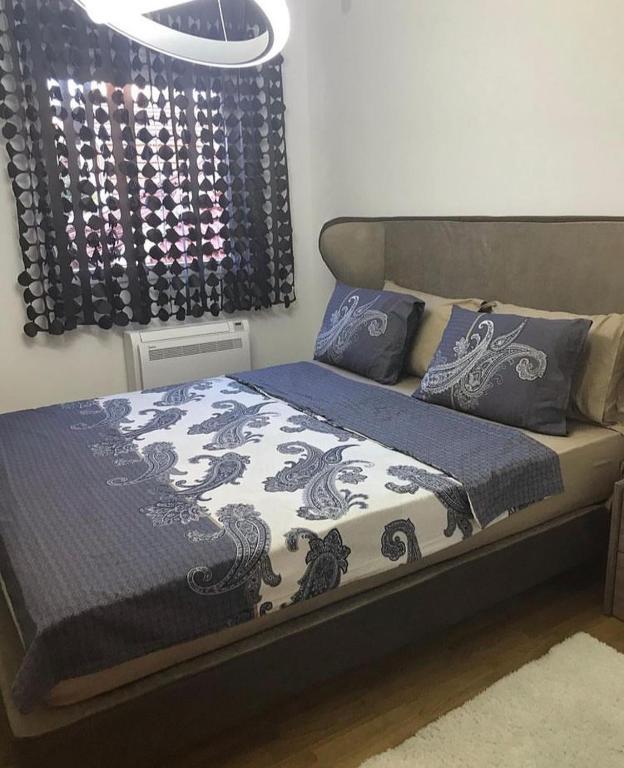 uma cama com um cobertor e almofadas azuis e brancas em Gabi apartman em Vranje