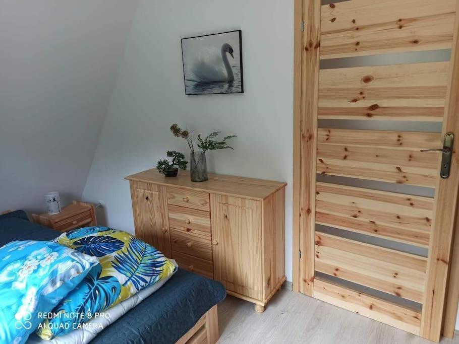 a bedroom with a bed and a wooden cabinet at Uroczy domek na Mazurach, Pilec 59 in Pilec