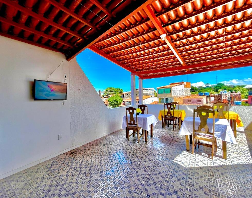 eine Terrasse mit Tischen und Stühlen und ein TV an der Wand in der Unterkunft Pousada Realce in Vera Cruz de Itaparica