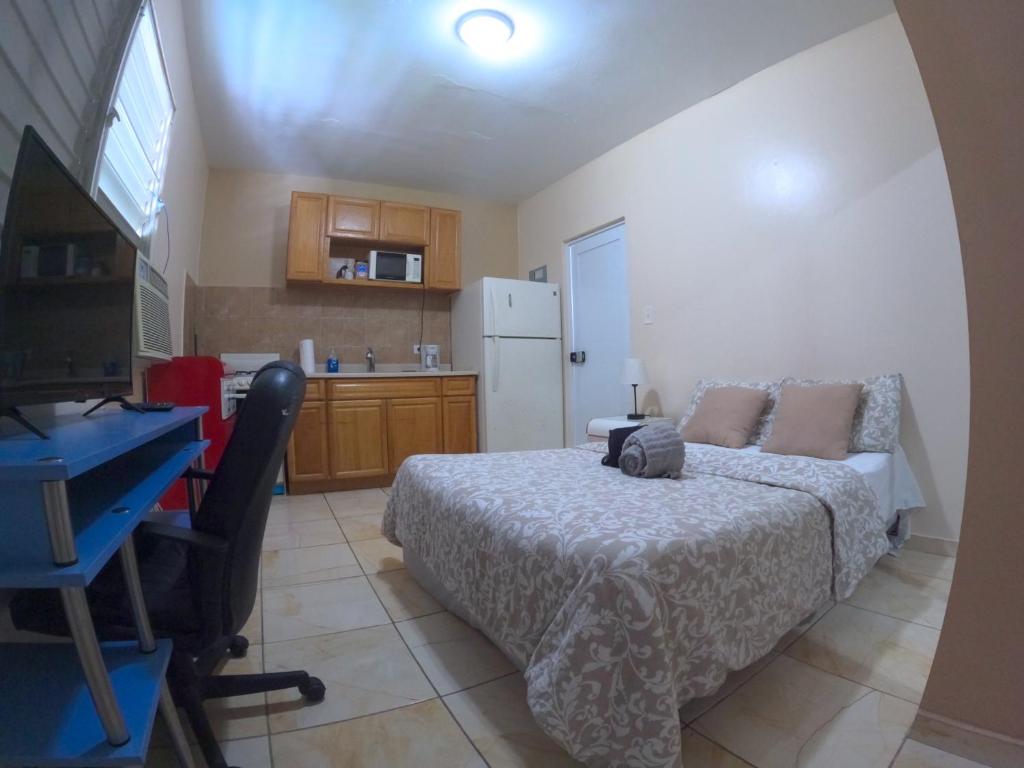 a bedroom with a bed and a desk and a kitchen at Apartament In Town Ponce- Free Wifi & Ac in Ponce