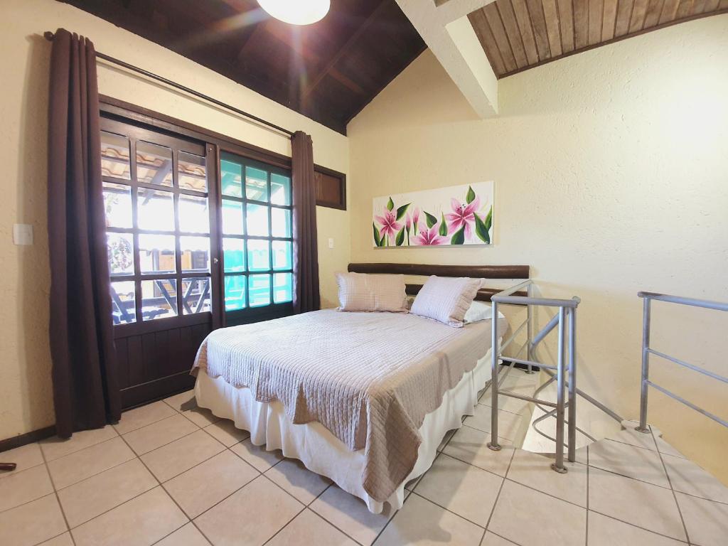 1 dormitorio con cama y ventana grande en Villa Garoupeta - Apartamentos, en Bombinhas