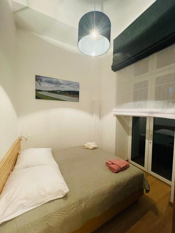 a bedroom with a bed and a lamp and a window at TALIA Apartament Tatarska 4 in Przemyśl