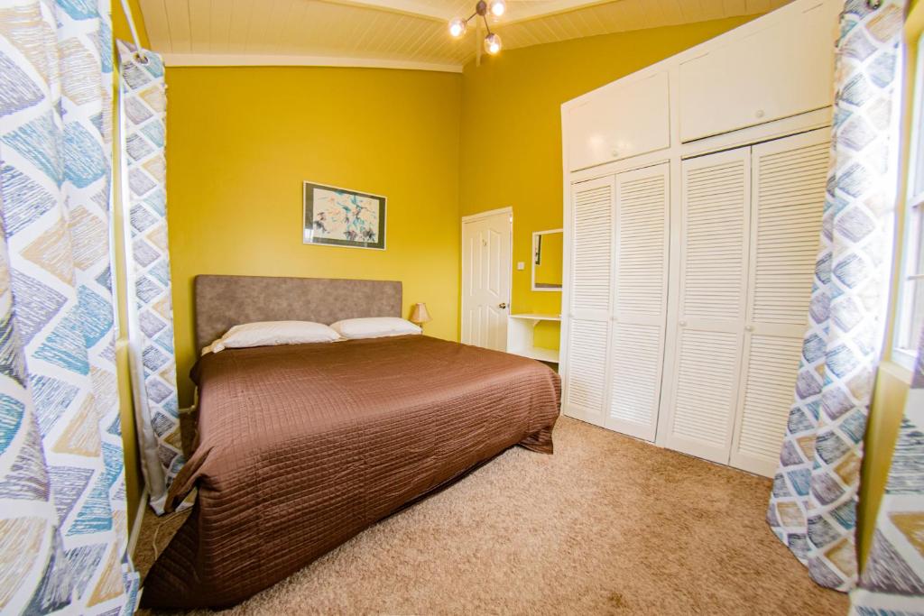 a bedroom with a bed and a yellow wall at JR Apartments in Georgetown