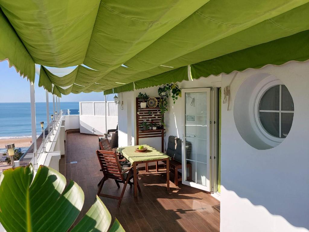 una mesa y sillas en un balcón con vistas a la playa en ÁTICO VICTORIA BEACH, en Cádiz