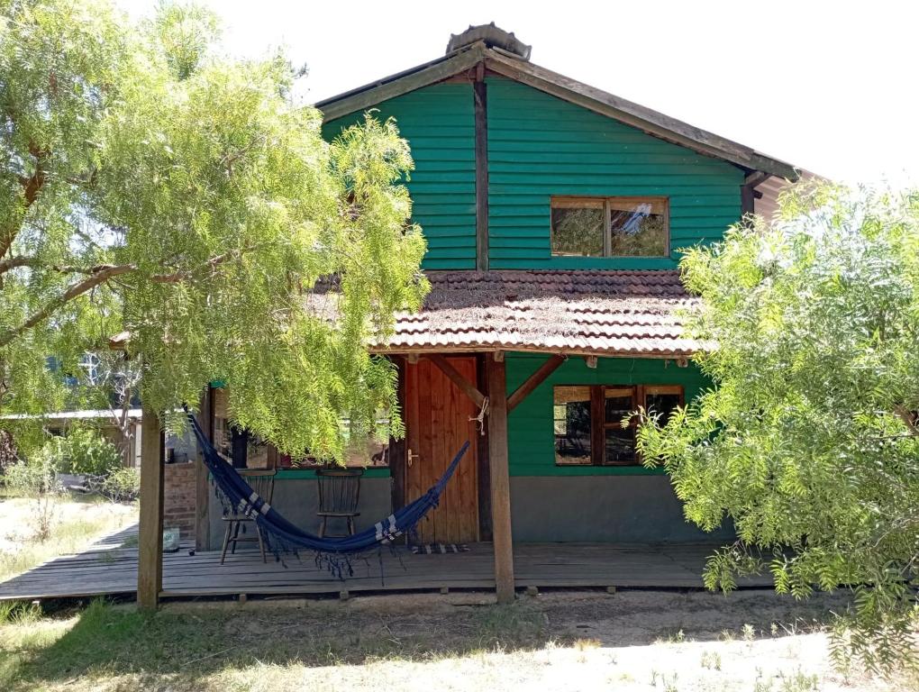 una casa verde con una hamaca delante en Natural Mistic, en Punta del Diablo