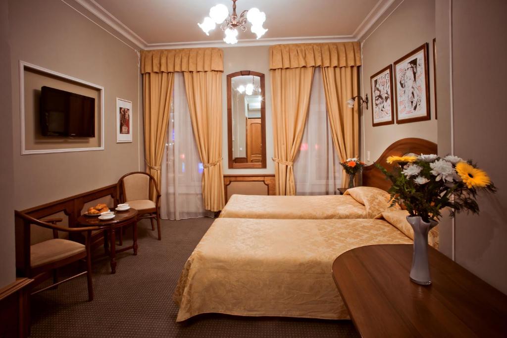 Old Vienna في سانت بطرسبرغ: غرفة نوم بسريرين وطاولة مع إناء من الزهور