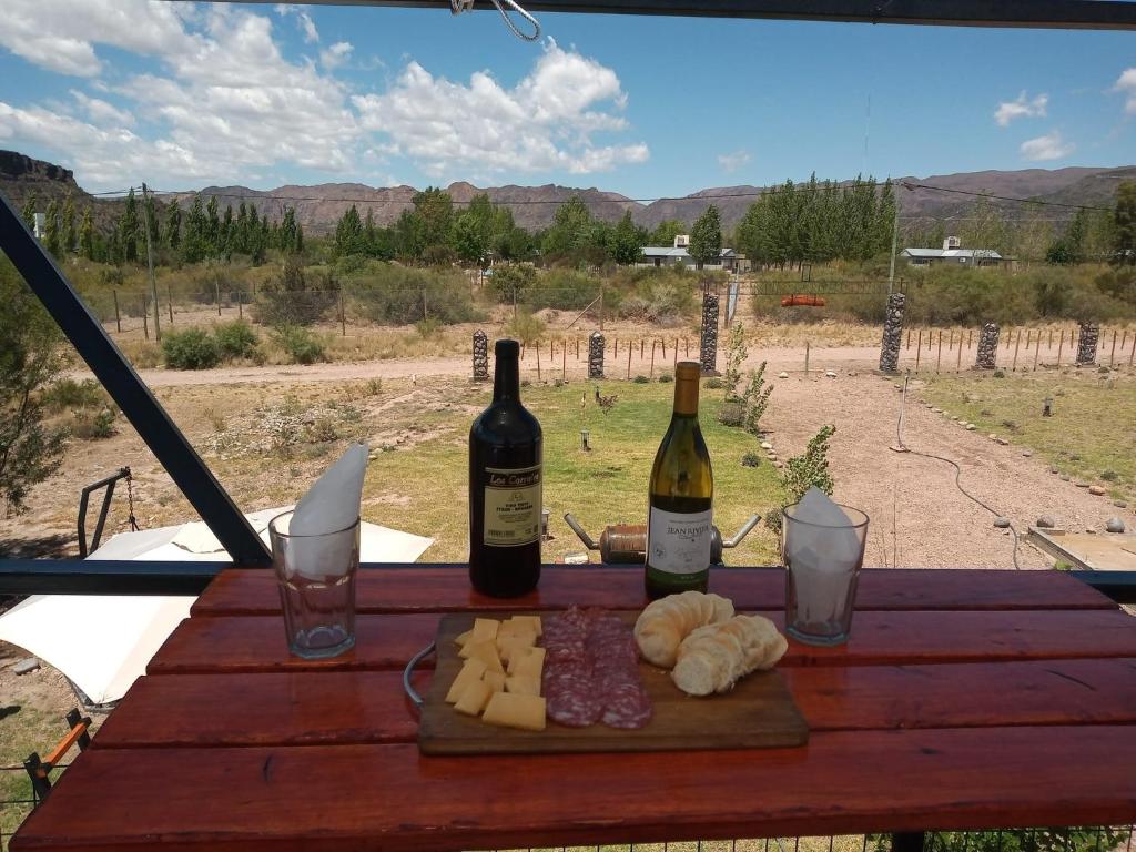 two bottles of wine and cheese on a wooden table at Balcon al Valle Grande, San Rafael Mendoza in Valle Grande
