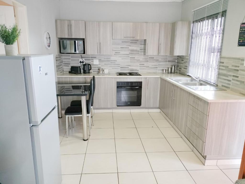 een witte keuken met een koelkast en een tafel bij Sunrise Guesthouse in Pretoria