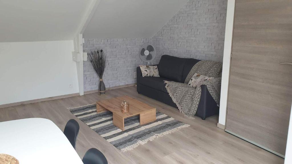 salon z czarną kanapą i stolikiem kawowym w obiekcie Le Gîte du Val de Noye w mieście Ailly-sur-Noye