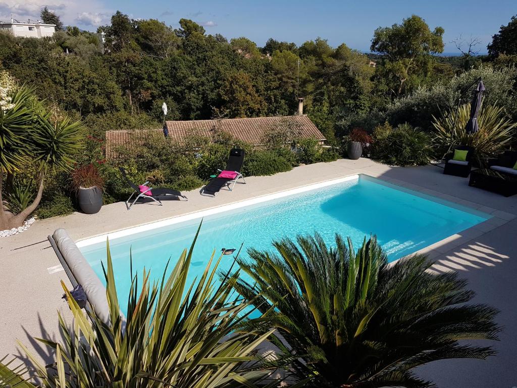 a swimming pool with two chairs in a yard at Mikado in La Gaude