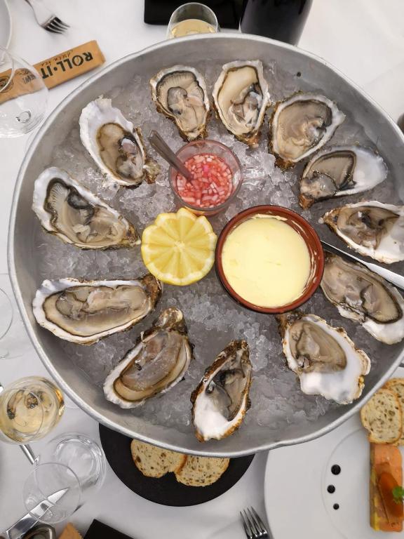 a plate of oysters on a table with sauce and a lemon at Maison confortable séjour spacieux, belle terrasse avec grand jardin avec jeux extérieurs près Bayeux et Omaha Beach in Saonnet