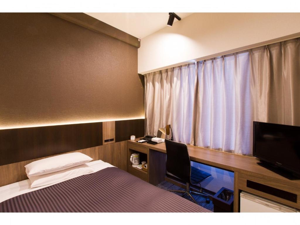 a bedroom with a bed and a desk and a television at Ochanomizu Inn - Vacation STAY 90241v in Tokyo