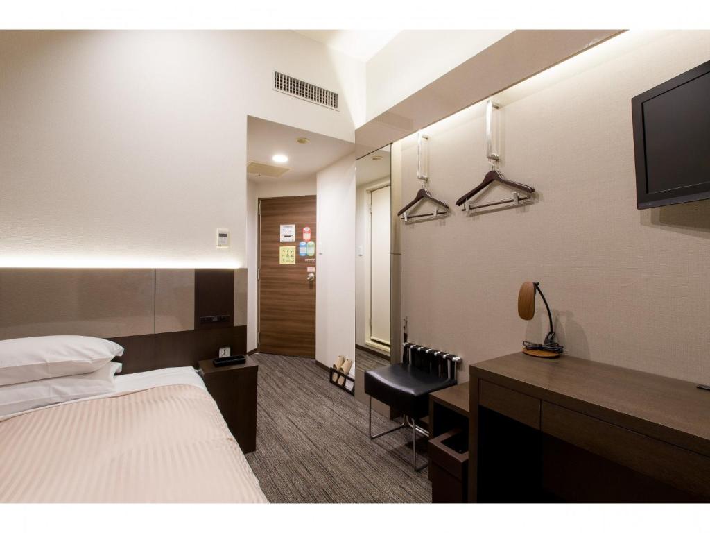 a hotel room with a bed and a desk and a television at Ochanomizu Inn - Vacation STAY 90277v in Tokyo