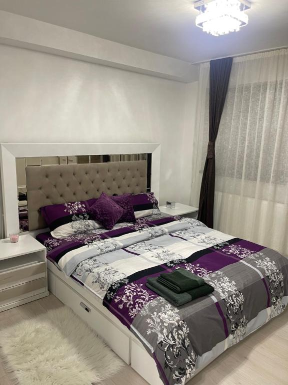 1 dormitorio con 1 cama grande con sábanas moradas y blancas en Discret Apartament One, en Târgovişte