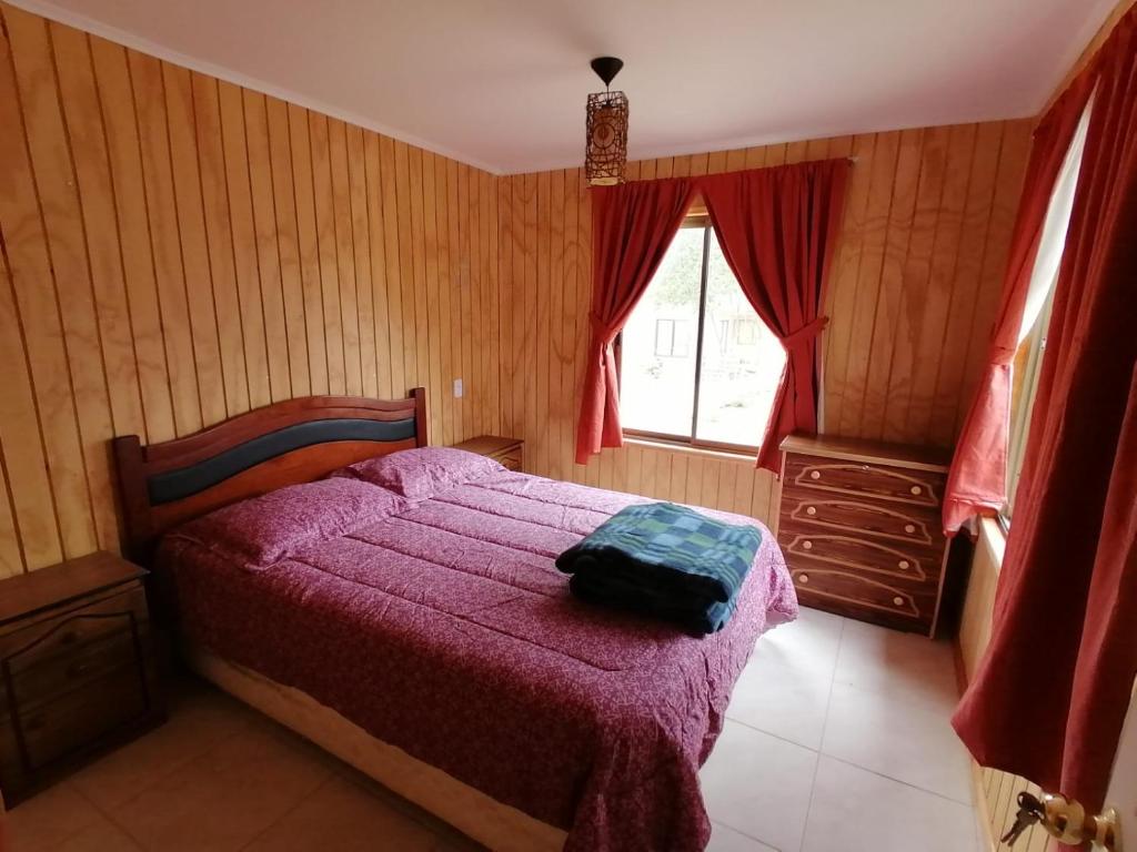 1 dormitorio con 1 cama con manta morada y ventana en Trinares de Olmue, en Granizo