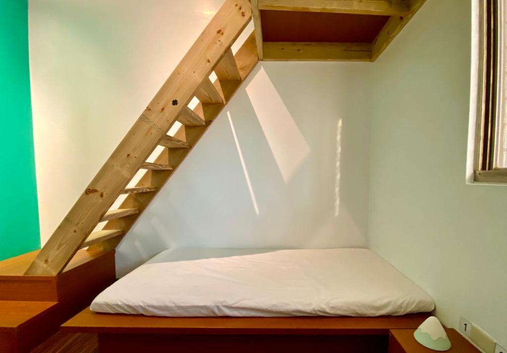 a bed in a small room with a staircase at 澎湖北吉光背包客民宿 Bayhouse Hostel Penghu in Magong